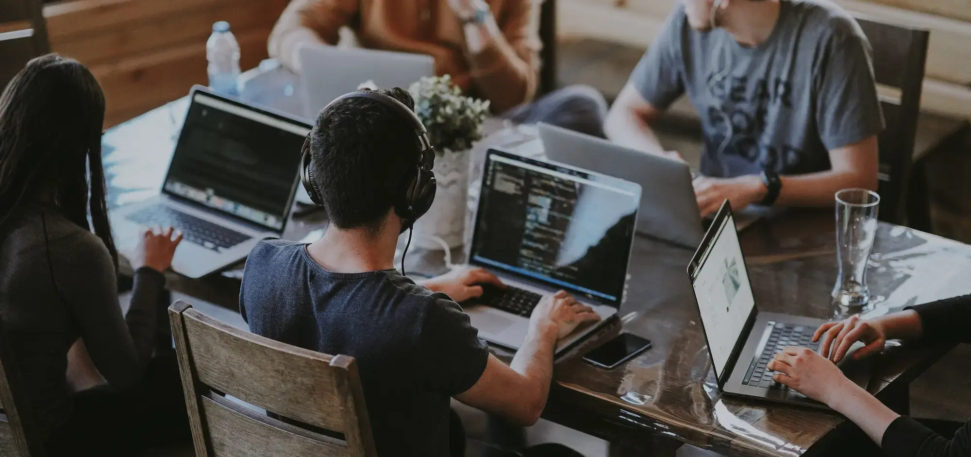 Few people sitting at a table, working on laptops